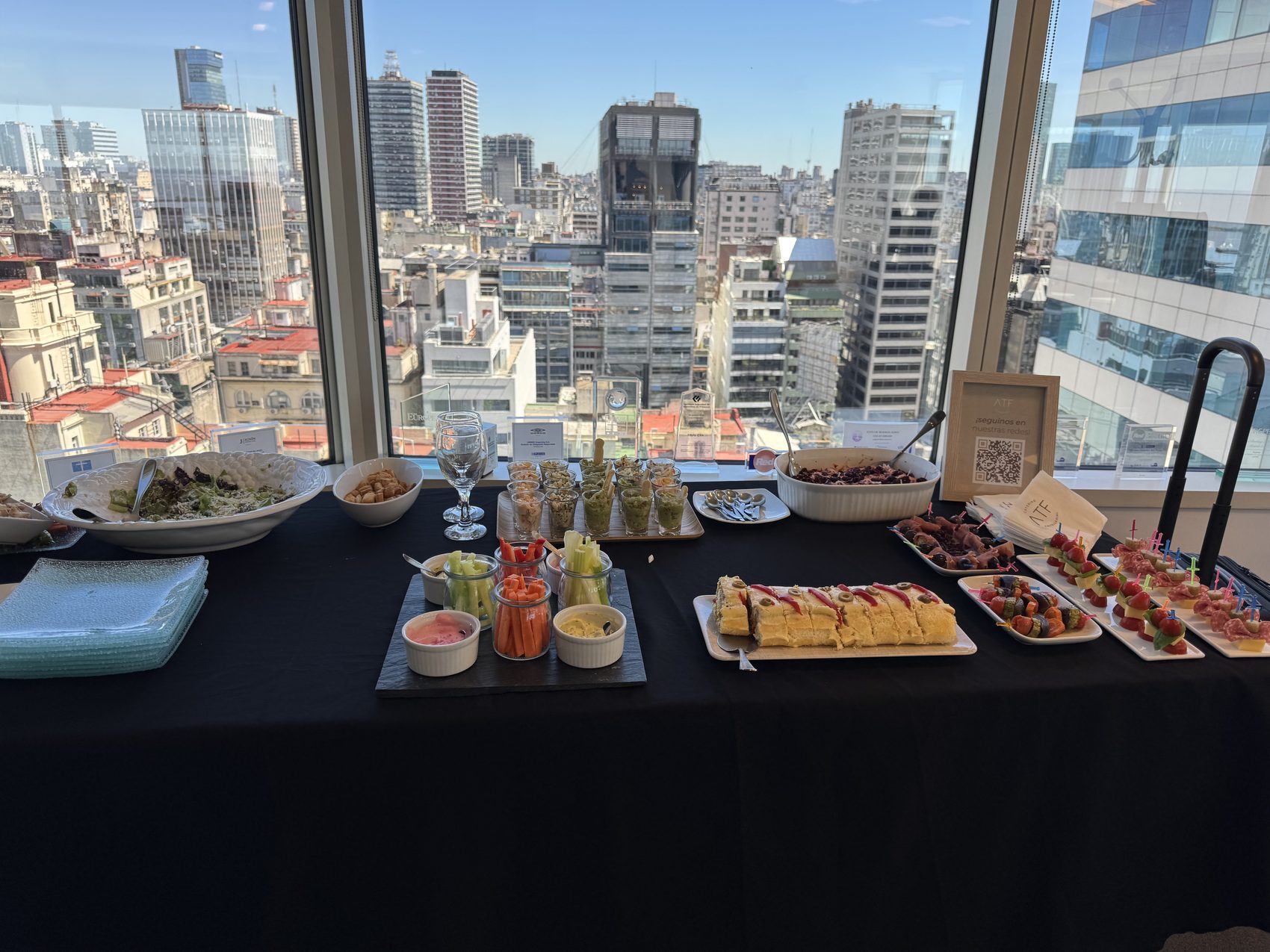 Mesa de catering ATF montada en oficina con vista al skyline de Buenos Aires